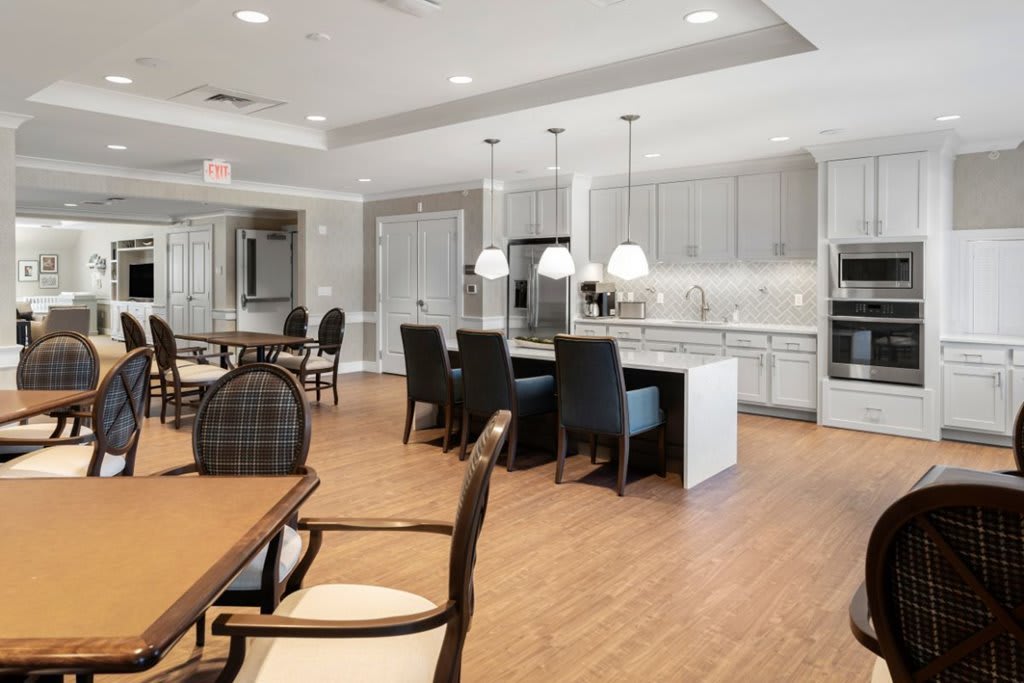 A modern open-concept kitchen and dining area featuring pendant lighting and wood flooring.