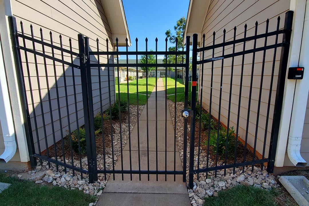 A metal gate leading to a pathway between two residential buildings.
