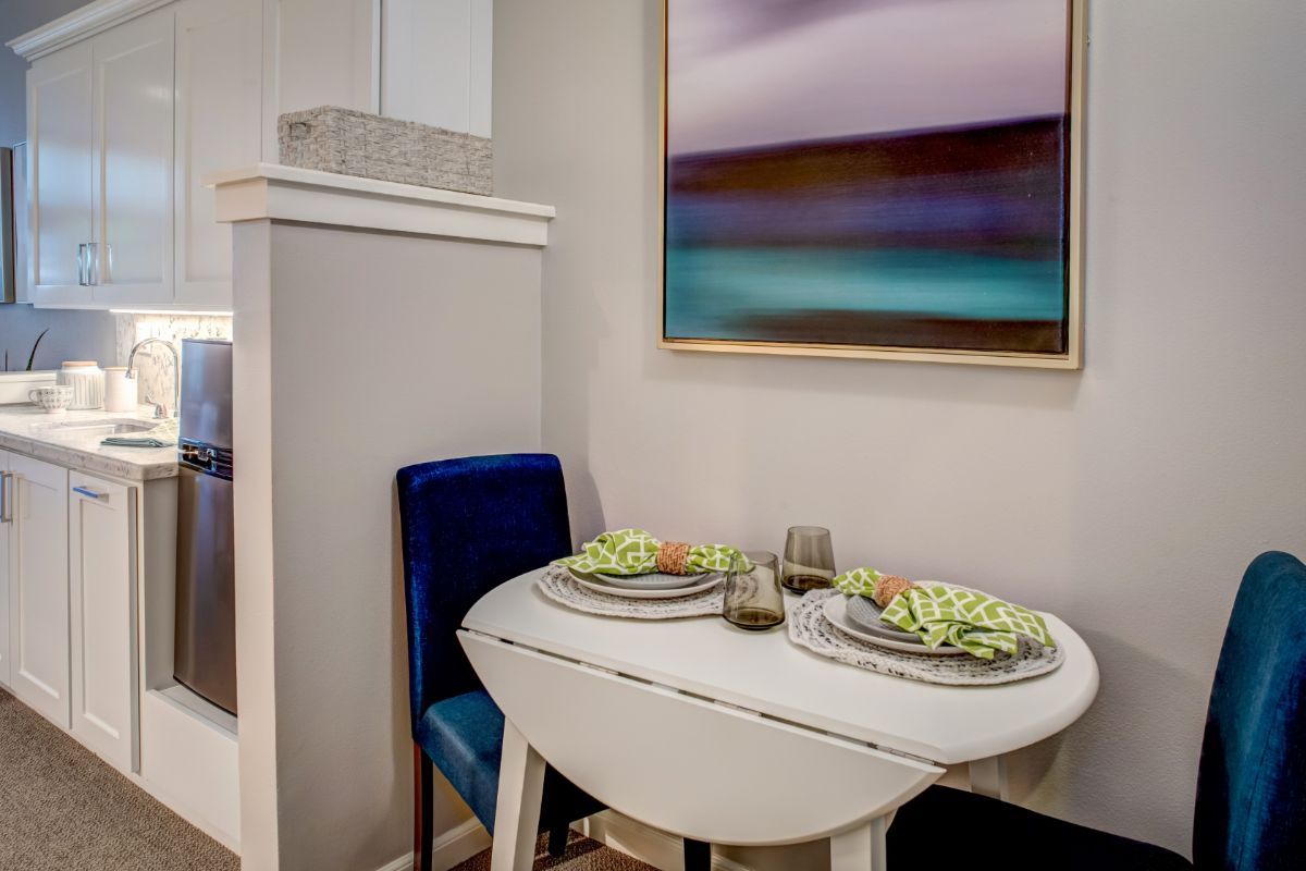 A cozy dining area with a small table set for two, accompanied by a colorful abstract painting.