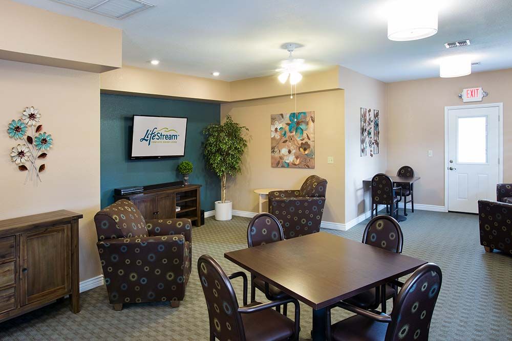 A cozy lounge area with comfortable seating and a television, decorated with artwork and a potted plant.