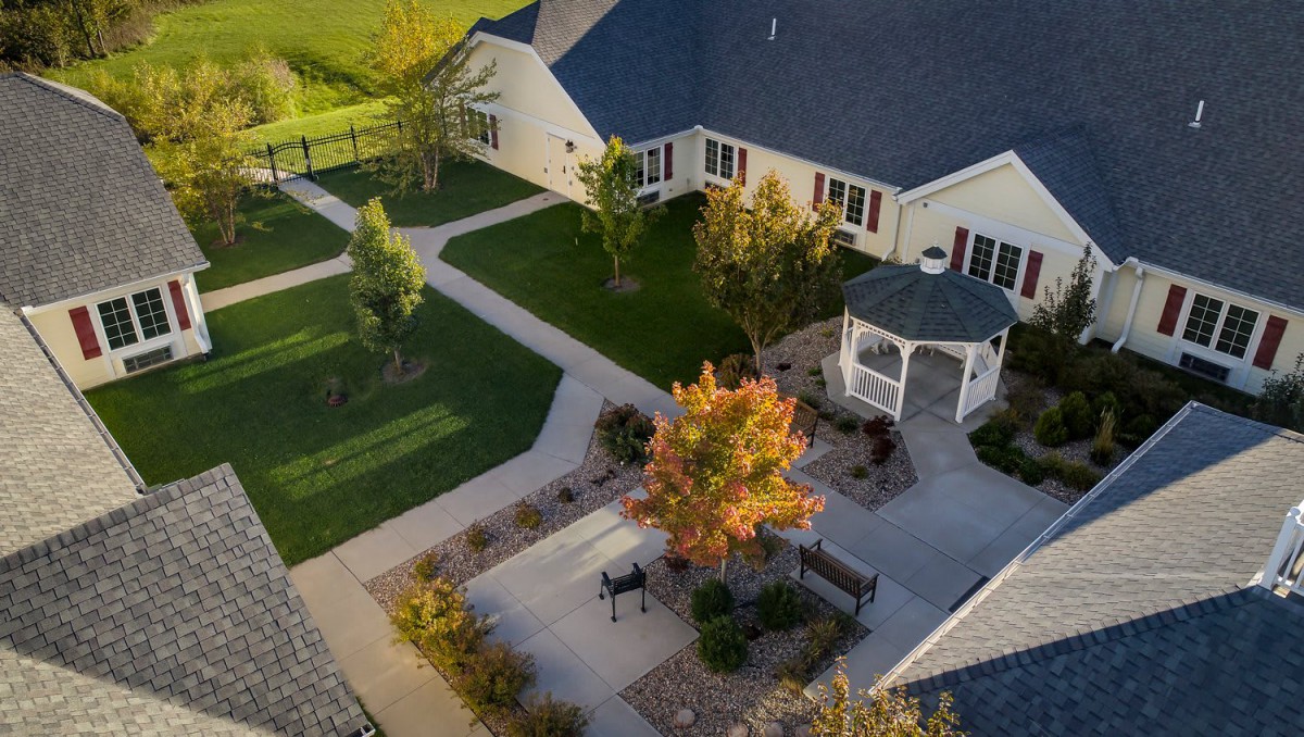 Aerial view of a house with a gazebo and landscaped garden pathways in autumn.