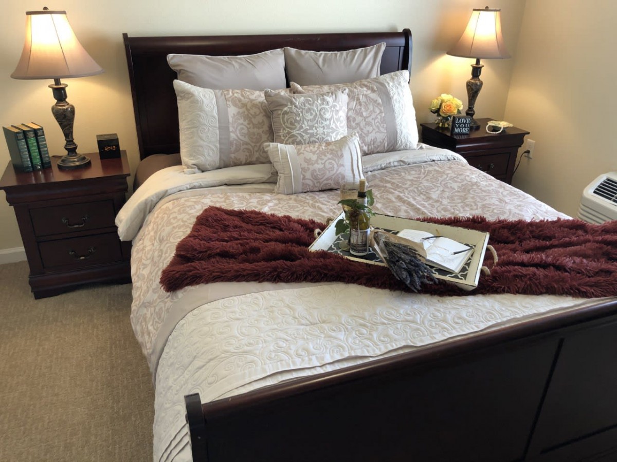 A cozy bedroom with a neatly arranged bed, featuring decorative pillows and a stylish tray.