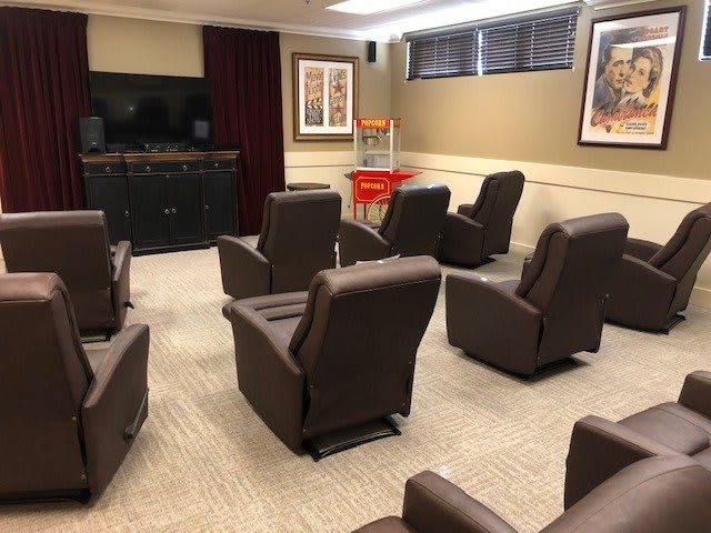 A cozy home theater with several recliner chairs arranged in rows, facing a large screen, ready for a movie night.