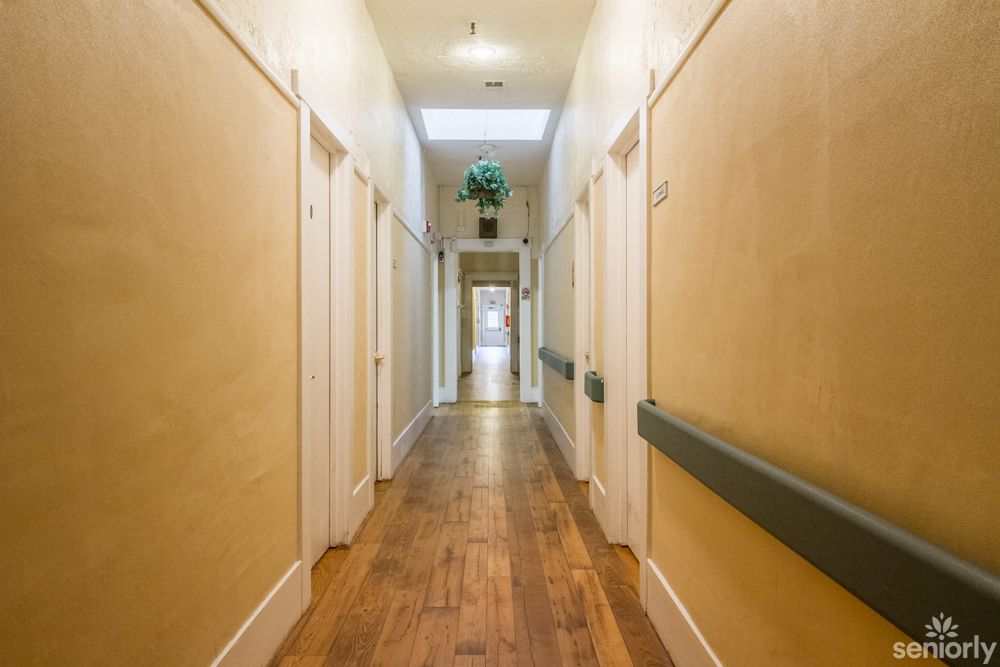 A long, well-lit hallway with wooden floors and multiple doors on either side.