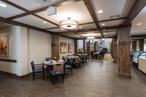A modern dining area with wooden accents, featuring tables, chairs, and decorative artwork.