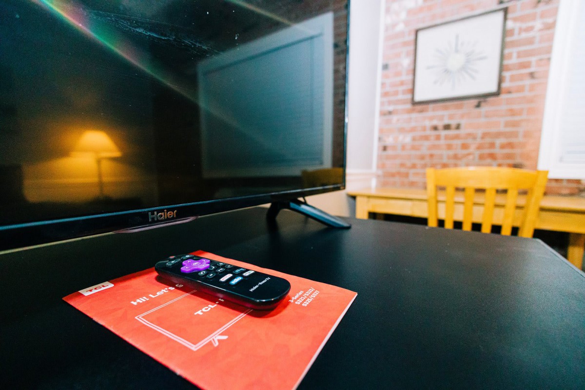 A TV with a remote control resting on a table in a cozy living room.