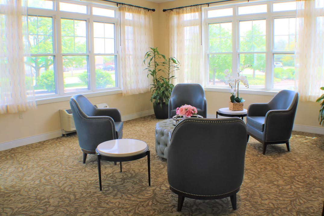 A cozy living room with comfortable chairs and a coffee table, surrounded by large windows.