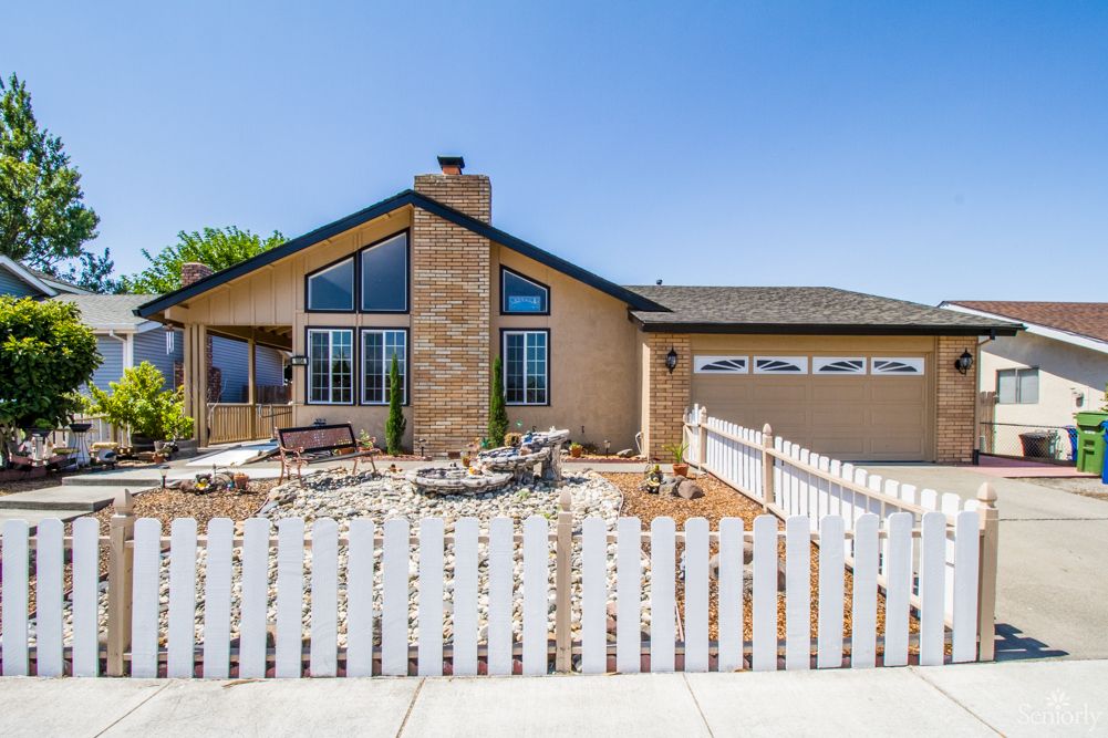 A single-story house with a white picket fence and a front yard.