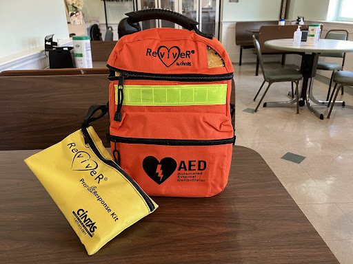 A bright orange medical backpack equipped for emergency situations, accompanied by a yellow pouch for additional supplies.