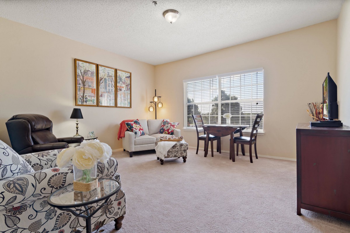 A cozy living room featuring a sofa, table, chairs, and decorative artwork.