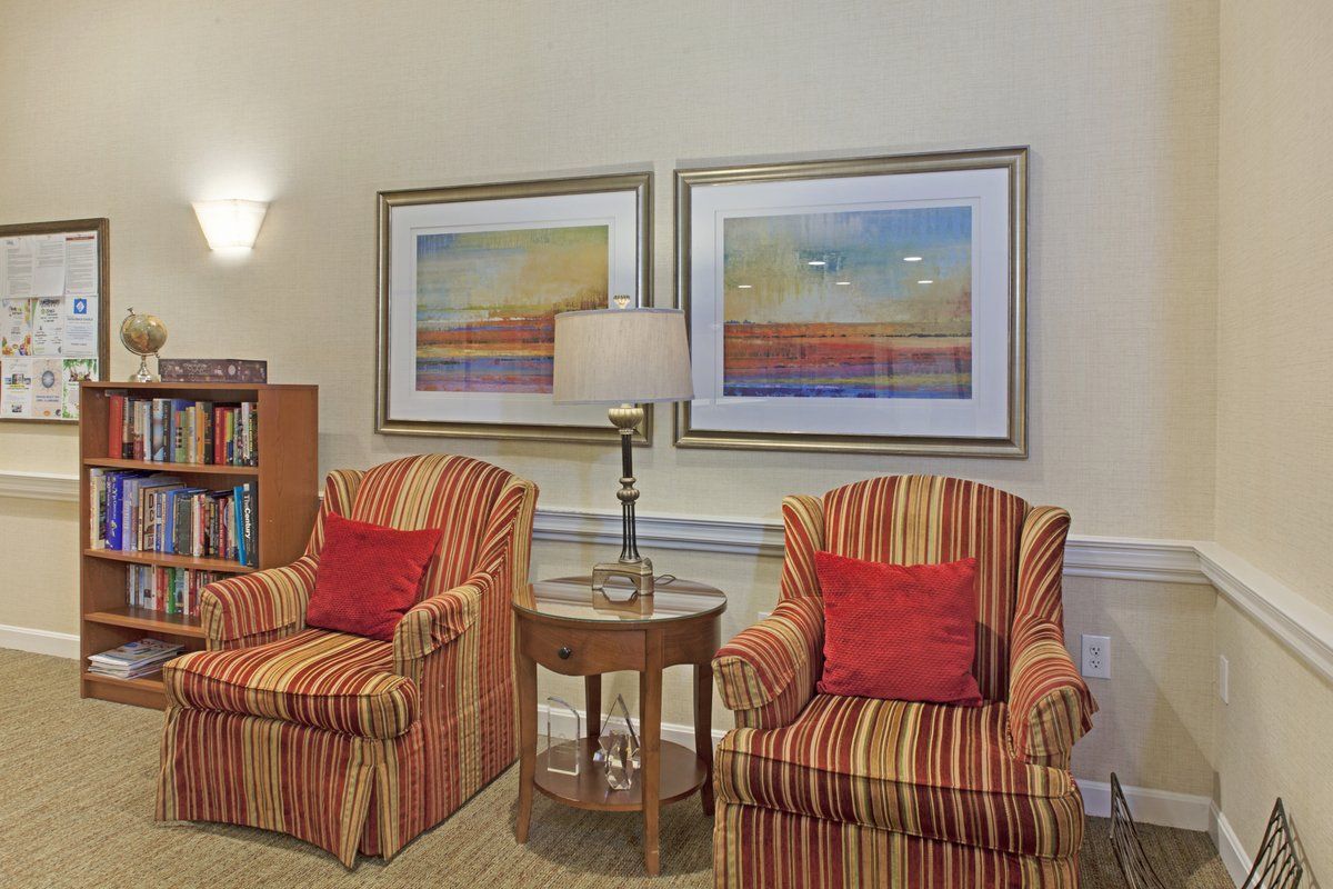 A cozy living room with striped armchairs and colorful artwork on the wall.