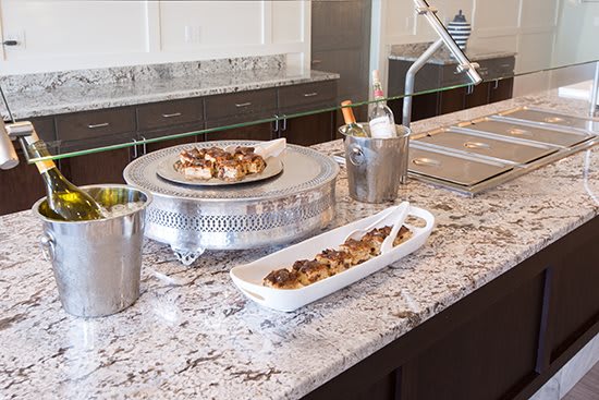 A kitchen countertop with serving dishes, featuring desserts and a champagne bucket.
