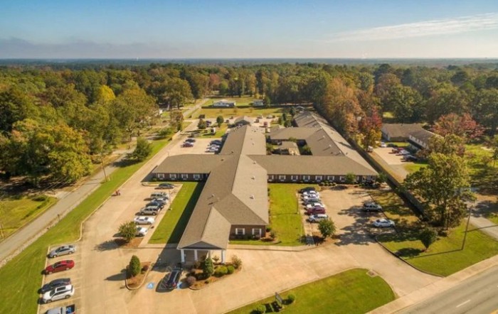 Aerial view of a large building complex with surrounding parking lots and greenery.