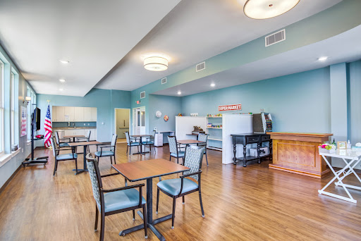 A spacious dining area featuring tables and chairs, with a modern design and blue walls.