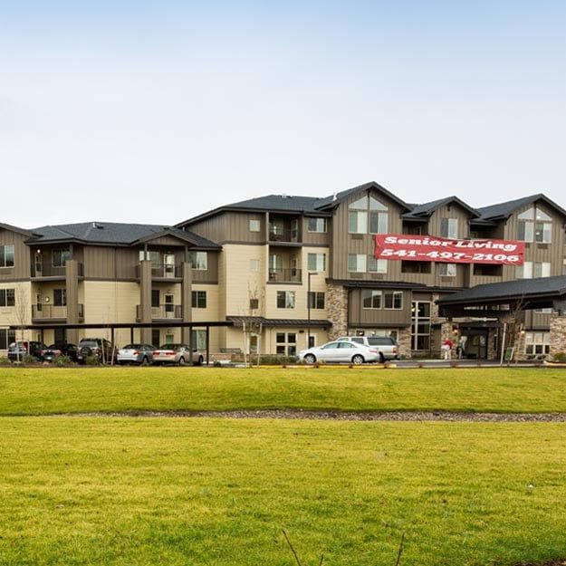 Exterior view of a hotel building with a well-maintained grass lawn in the foreground.