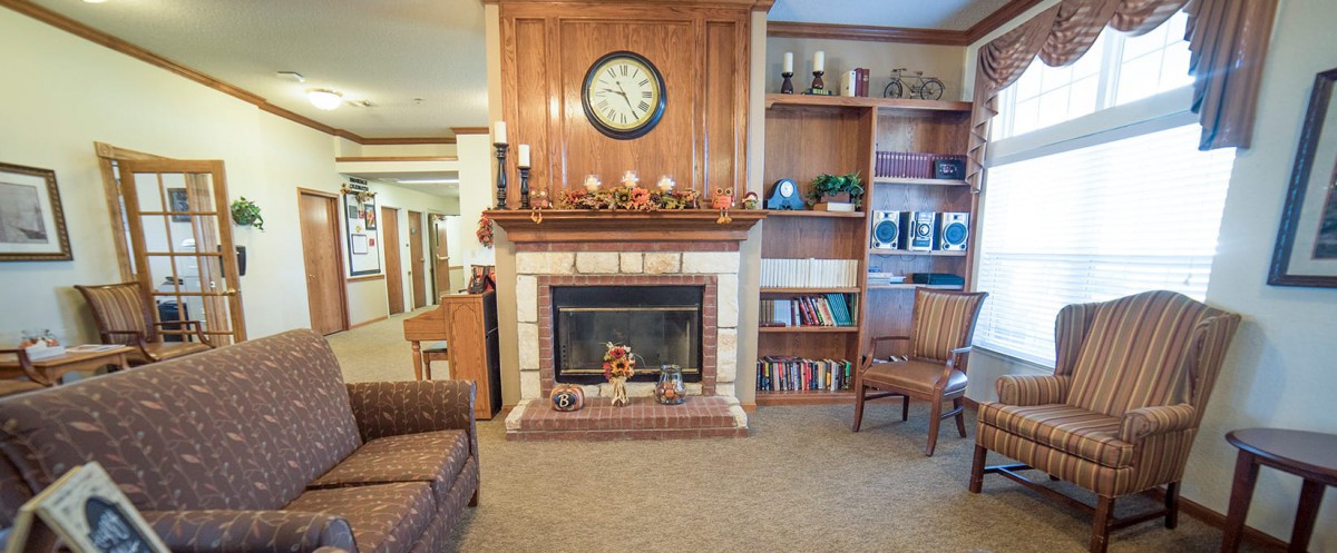 A cozy living room with a fireplace, clock, and bookshelves.