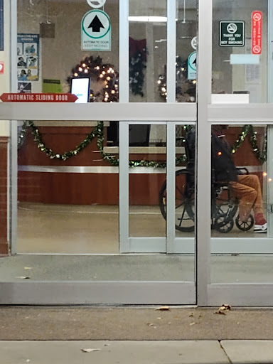 A view of a shopping center entrance, adorned with holiday decorations, featuring a person in a wheelchair.