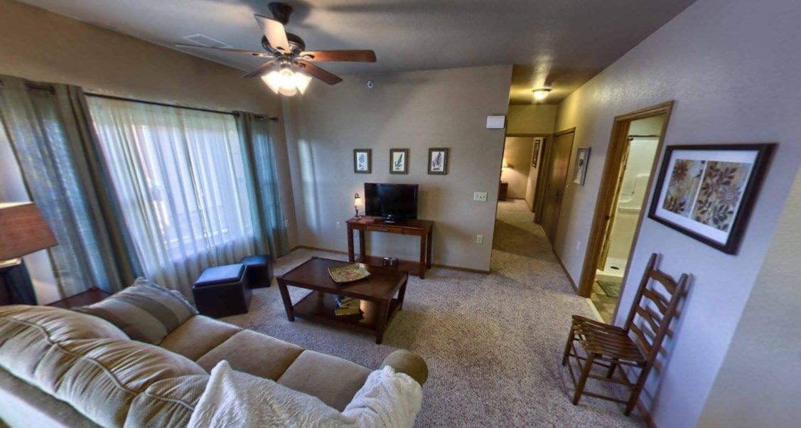 A cozy living room with a sofa, coffee table, and television under a ceiling fan.