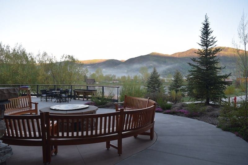 A scenic patio area overlooking misty mountains and lush greenery at sunrise.