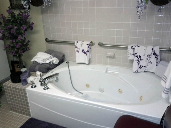 A cozy bathroom featuring a large bathtub with floral towels and decorative elements.