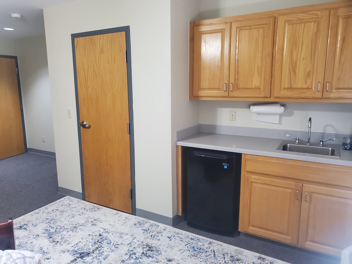 A small kitchen area with wooden cabinets, a sink, and a refrigerator.