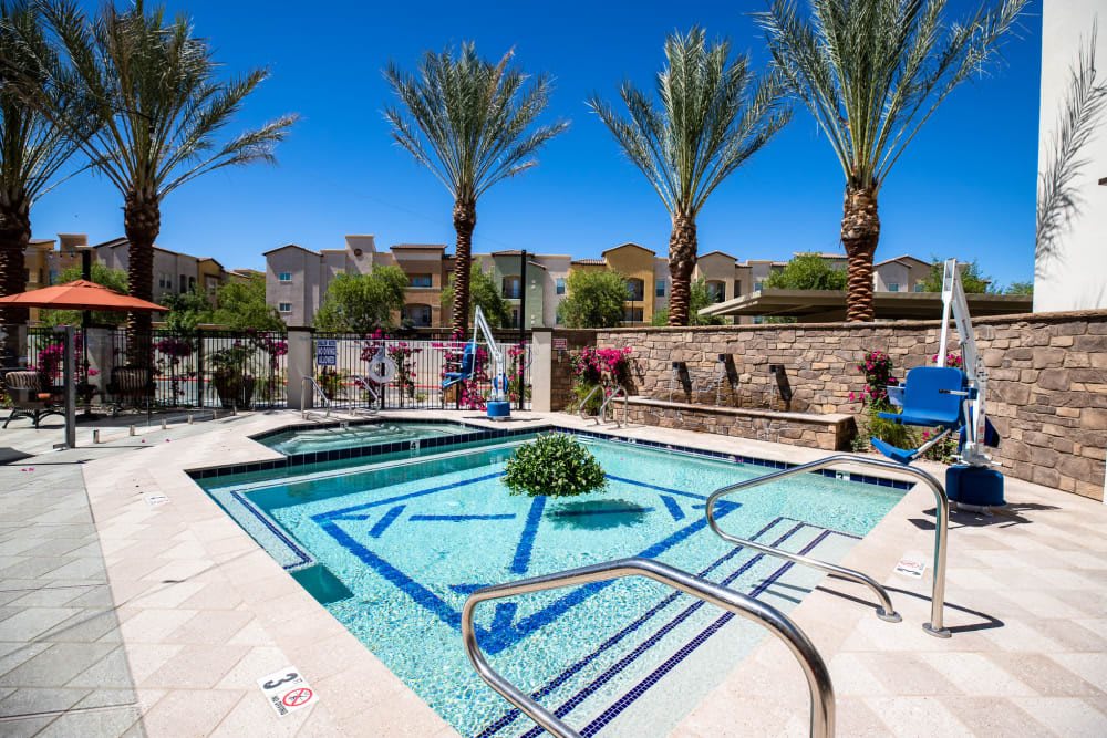 A luxurious outdoor pool surrounded by palm trees and vibrant landscaping on a sunny day.