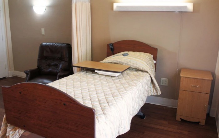 A hospital bed in a healthcare setting with a side table attached.