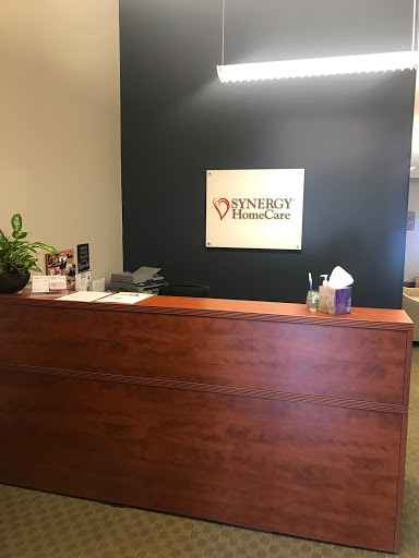 A reception area of a medical office featuring a wooden desk and healthcare signage.