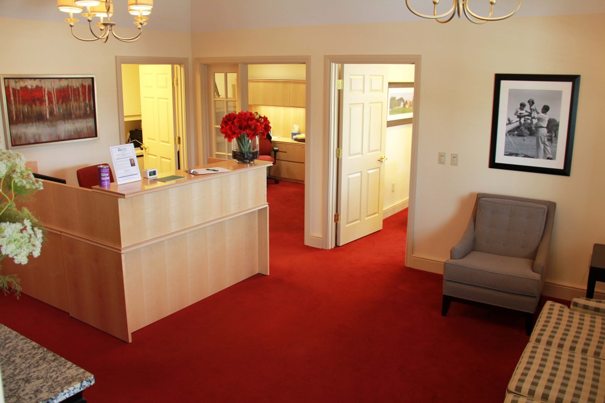 A cozy office reception area with a red carpet and comfortable seating.