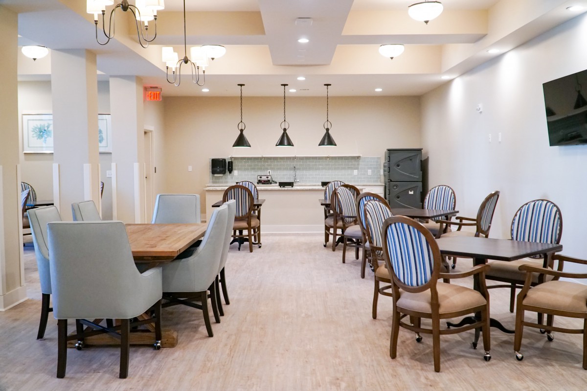 A cozy dining area with several tables and chairs, softly lit by overhead lights.