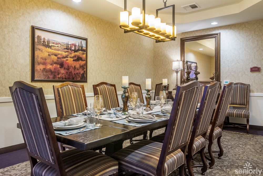 A beautifully set formal dining room with elegant chairs and a chandelier.