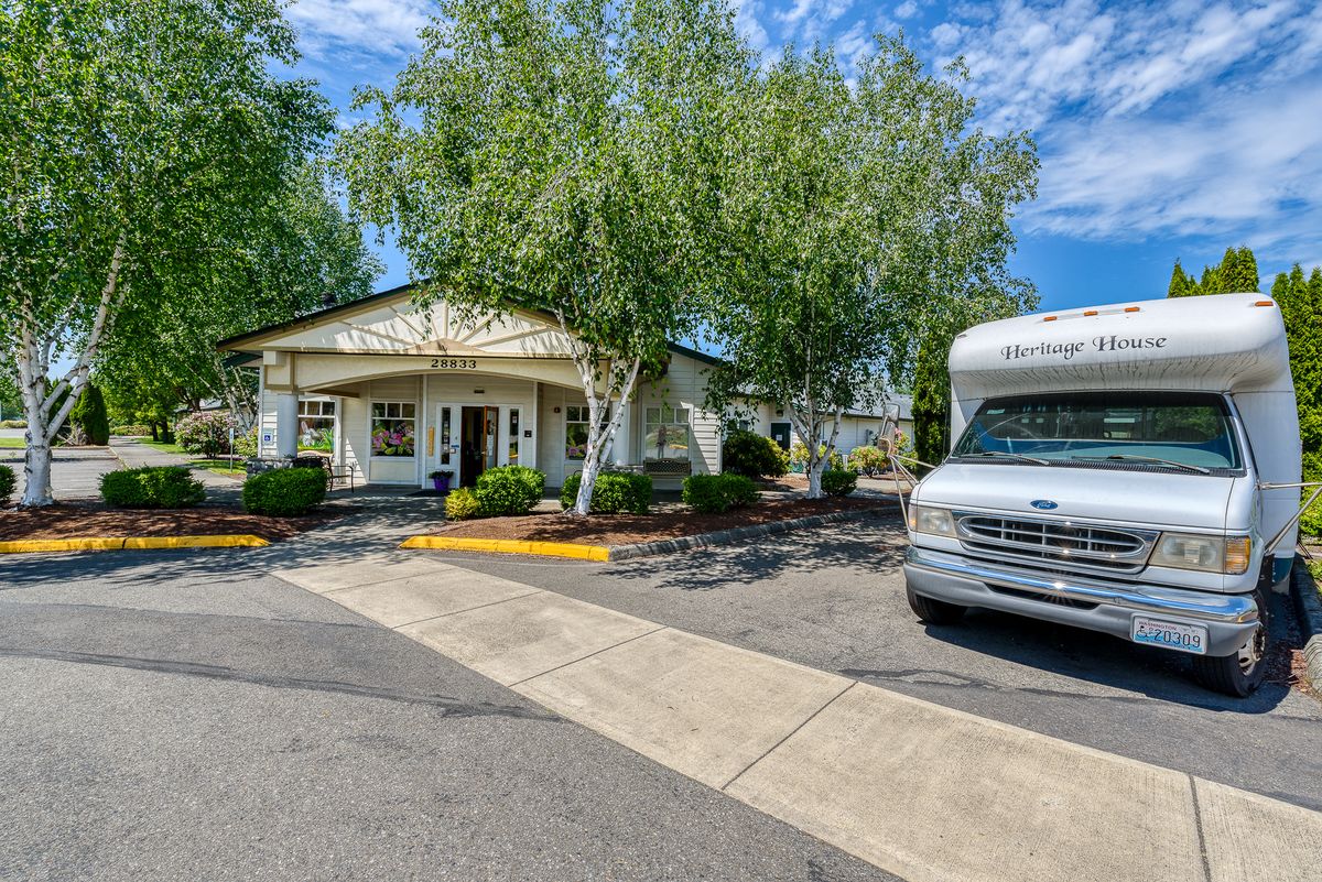 A small white building with a bus parked outside on a sunny day.
