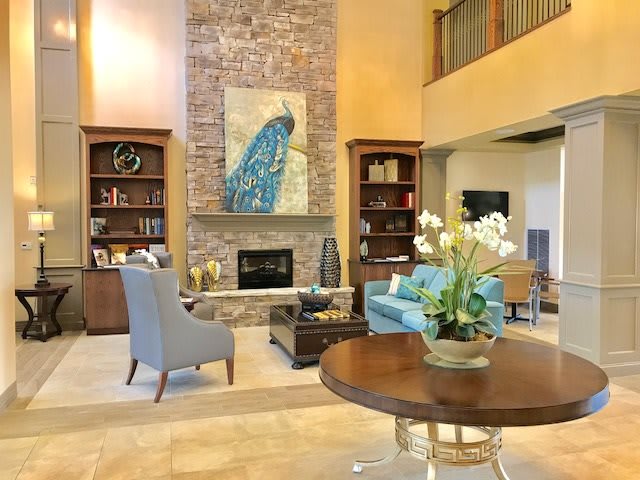 A stylish living room with a high ceiling, featuring a prominent fireplace, elegant furniture, and artistic decor.