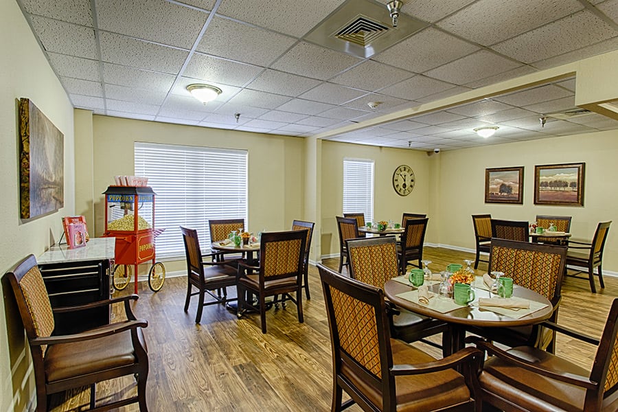 A cozy dining area with several tables and chairs, featuring a popcorn machine and wooden flooring.