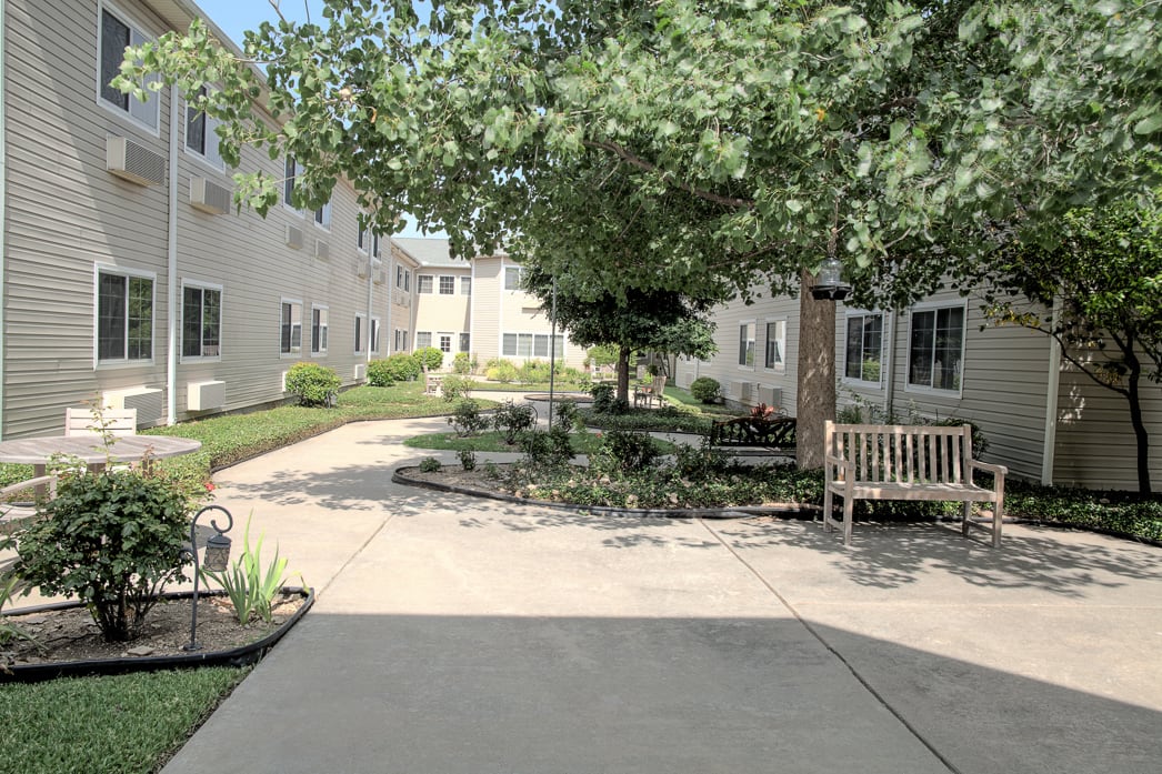 A peaceful courtyard with benches and trees, surrounded by residential buildings.