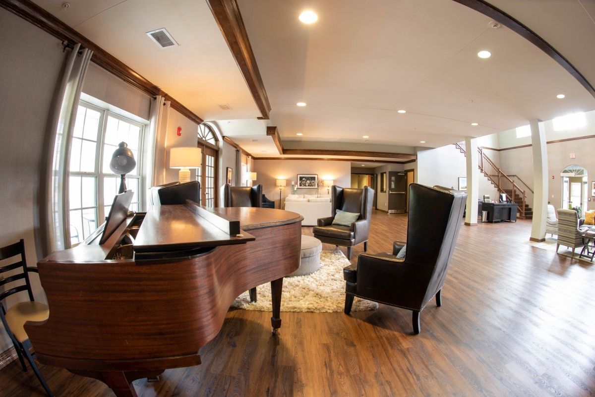 A cozy living room with a grand piano and stylish armchairs on a wooden floor.