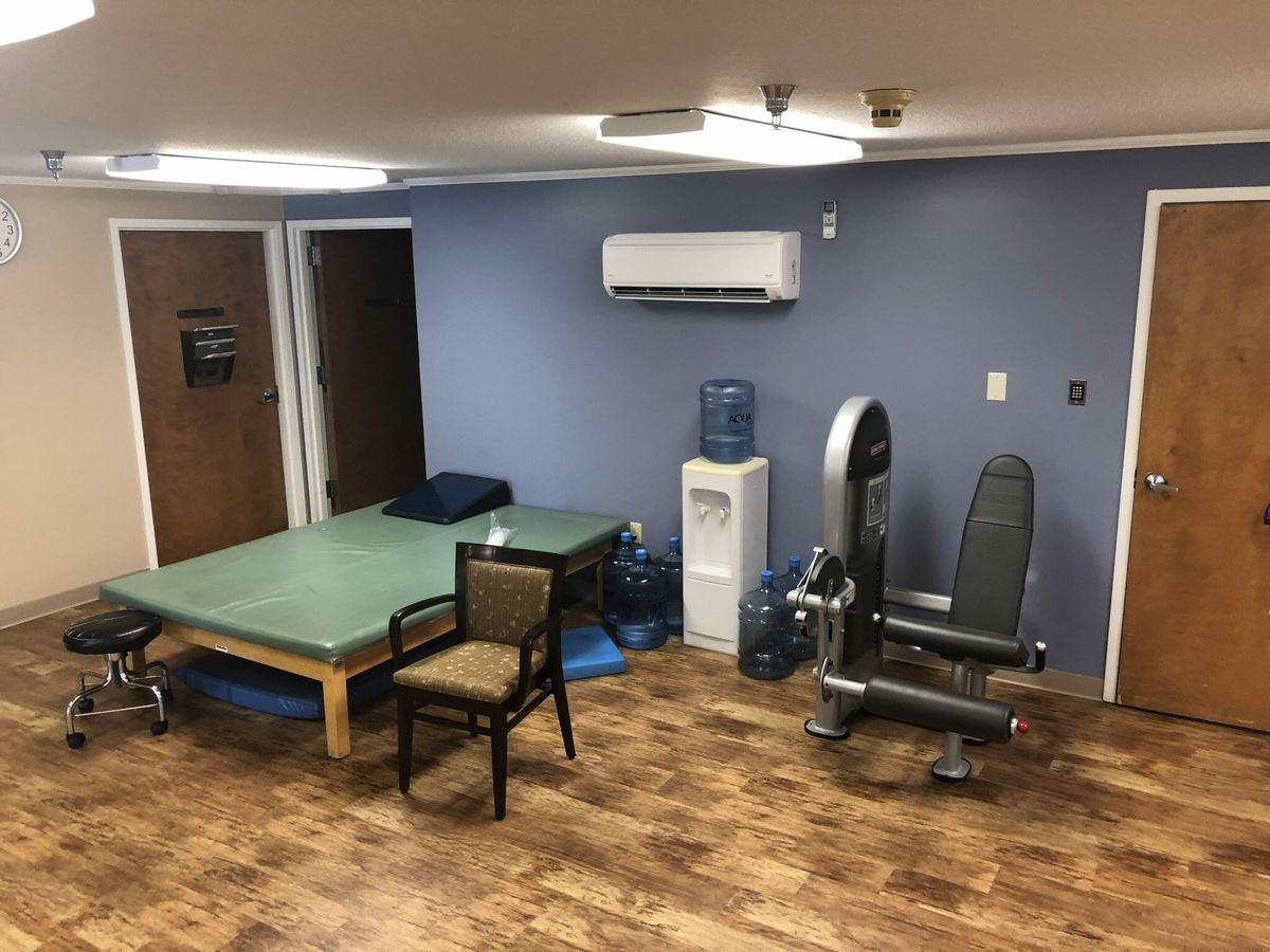 A physical therapy room with exercise equipment and a treatment table.