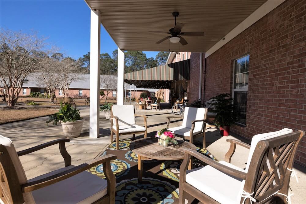 A cozy outdoor patio with comfortable seating, a table, and potted plants under a clear blue sky.