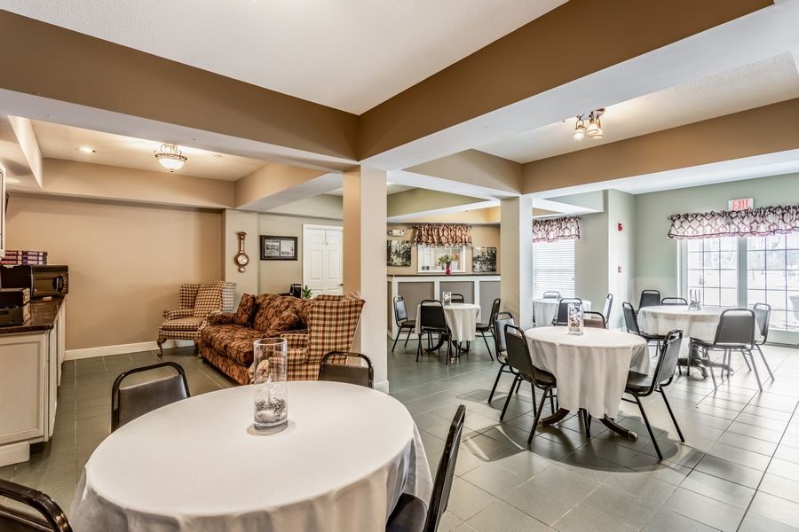A cozy indoor dining area with round tables, chairs, and a sofa in the background.