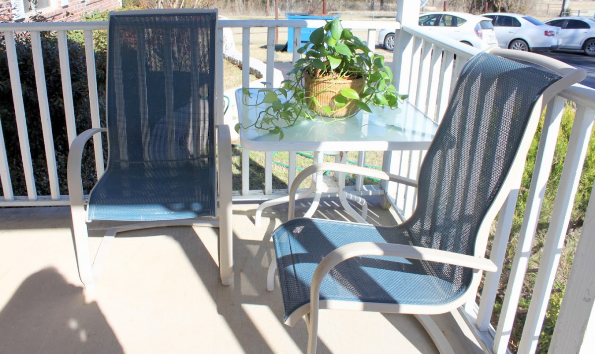 A sunny patio with outdoor furniture and a potted plant on the table.