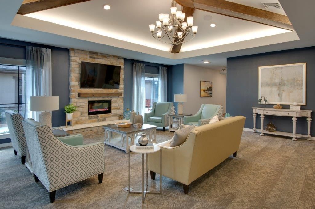 A modern living room with elegant furnishings, featuring a fireplace and a chandelier.