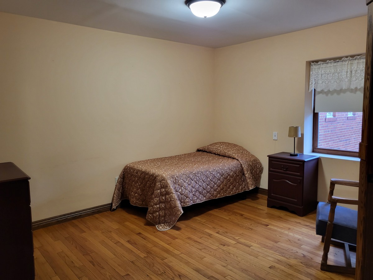 A minimalist bedroom with a single bed, nightstand, and window.