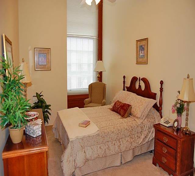 A cozy bedroom with elegant decor, featuring a neatly made bed, wooden furniture, and some indoor plants.