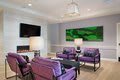 A modern living room with purple chairs and a large green artwork on the wall.