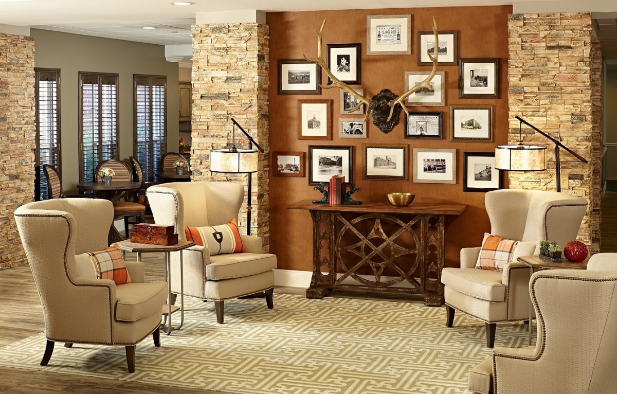 A cozy living room featuring two armchairs, a console table adorned with decorative items, and a gallery wall of framed art.