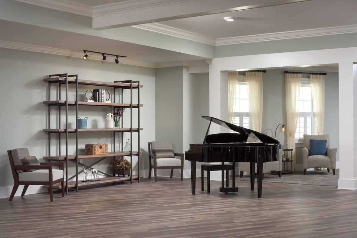 A spacious living room with a grand piano and stylish shelving.