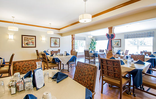 A well-lit restaurant dining area with neatly arranged tables and chairs, featuring elegant interior decor.