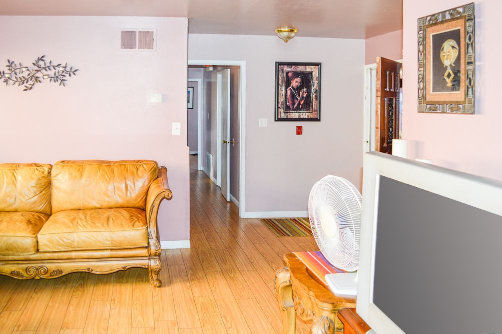 A cozy living room with a sofa, television, and a hallway leading to other rooms.