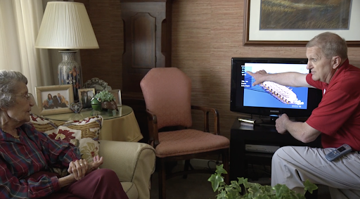 A cozy living room setup featuring a sofa, an armchair, a table lamp, and a television.