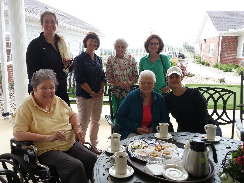 A group of women enjoying a gathering on a patio with coffee and snacks.